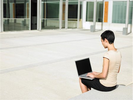 Young woman sitting in plaza courtyard  using laptop Stock Photo - Premium Royalty-Free, Code: 693-03564961