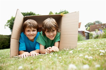 Two in backyard lying in cardboard box, portrait Stock Photo - Premium Royalty-Free, Code: 693-03565025