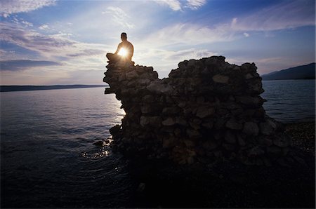 Man sitting on rock overlooking ocean Stock Photo - Premium Royalty-Free, Code: 693-03565084