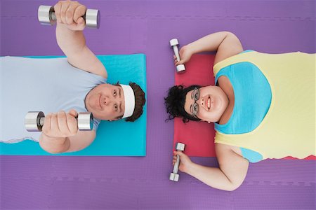 simsearch:693-06016281,k - Overweight man and woman lying down lifting dumbbells, overhead view Stock Photo - Premium Royalty-Free, Code: 693-03565334