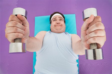 simsearch:693-03557462,k - Overweight Man lying down Lifting dumbbells, overhead view Stock Photo - Premium Royalty-Free, Code: 693-03565331