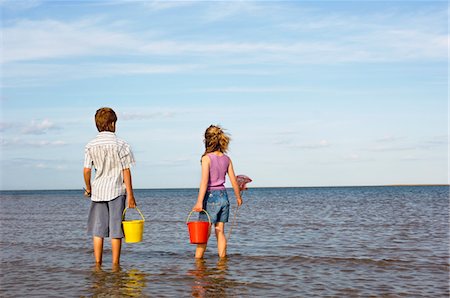 simsearch:693-03304327,k - Brother and Sister in surf on beach with buckets and small fishnets looking out at ocean, back view Foto de stock - Sin royalties Premium, Código: 693-03565414