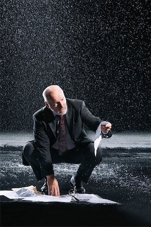 Businessman Picking up soaked Paperwork during downpour Stock Photo - Premium Royalty-Free, Code: 693-03565498