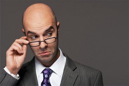 Balding businessman hand on glasses, making a face Stock Photo - Premium Royalty-Free, Code: 693-03565560