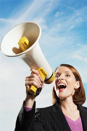 Smiling Mid-adult woman shouting through megaphone outside Stock Photo - Premium Royalty-Free, Code: 693-03565577