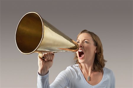 Angry, Mid-adult woman shouting through megaphone Stock Photo - Premium Royalty-Free, Code: 693-03565570