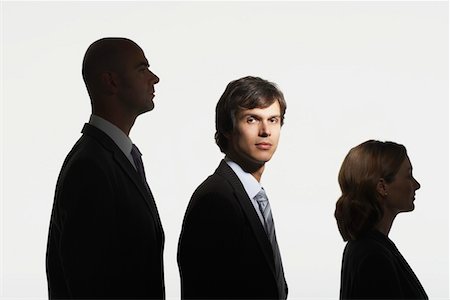 Businesspeople standing in row, in height order, middle man facing camera in spotlight Stock Photo - Premium Royalty-Free, Code: 693-03565573