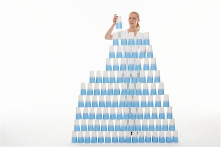 plastikbecher - Frau Stapeln Plastikbecher in Pyramide vor weißem Hintergrund Stockbilder - Premium RF Lizenzfrei, Bildnummer: 693-03565592