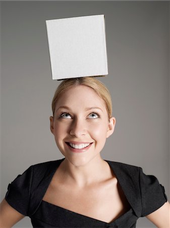 Young woman in black dress with white box on her head Stock Photo - Premium Royalty-Free, Code: 693-03565605