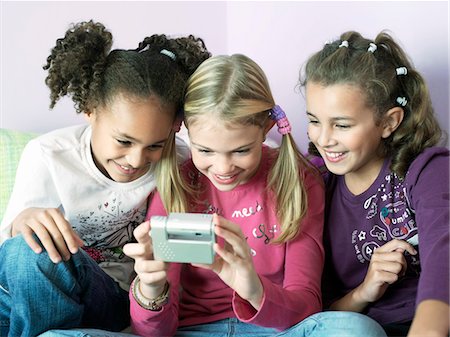 Girls sitting side by side playing with electrical gadget Stock Photo - Premium Royalty-Free, Code: 693-03565671