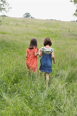 Two girls (7-9) holding hands in field Stock Photo - Premium Royalty-Free, Code: 693-03565738
