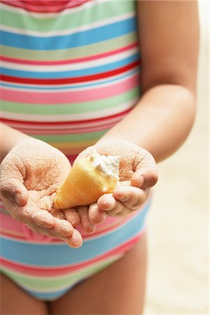 Girl (7-9 years) holding sea shell in clasped hands, mid section, elevated view Stock Photo - Premium Royalty-Free, Code: 693-03565744