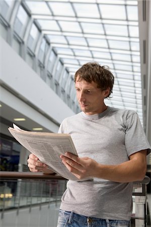 Young man stands reading newspaper in new shopping centre, Voronezh Stock Photo - Premium Royalty-Free, Code: 693-03644005