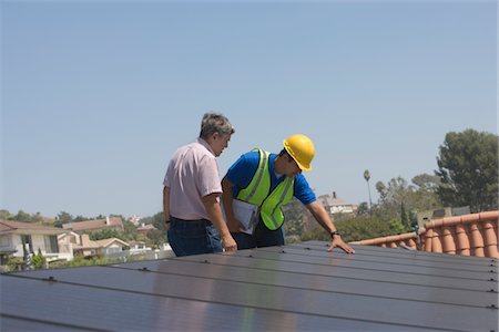 solar power usa - Maintenance workers stand with solar array on rooftop in Los Angeles, California Foto de stock - Sin royalties Premium, Código: 693-03643969