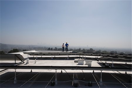 solar power usa - Maintenance workers stand with solar array on rooftop in Los Angeles, California Foto de stock - Sin royalties Premium, Código: 693-03643973