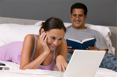 Couple Relaxing on Bed, woman using Laptop Stock Photo - Premium Royalty-Free, Code: 693-03686278
