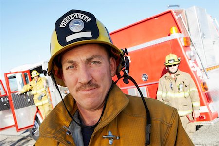 fireman portrait - Fire fighter standing in front of colleagues and fire engine Stock Photo - Premium Royalty-Free, Code: 693-03686513