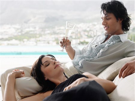 Man drinking champagne with woman lying on his lap on balcony Stock Photo - Premium Royalty-Free, Code: 693-03686715