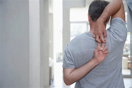 Man standing, stretching arms behind back, back view Stock Photo - Premium Royalty-Free, Code: 693-03686729