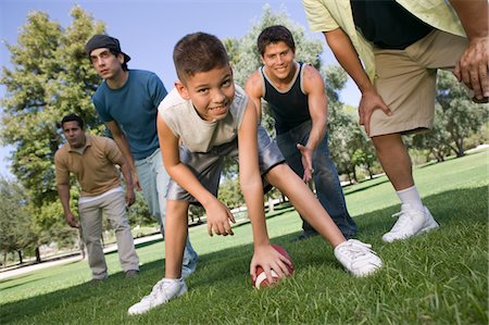 friends playing football - Boy (13-15) playing football with group of men. Stock Photo - Premium Royalty-Free, Code: 693-03706959
