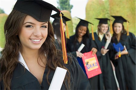 Graduate Holding Diploma outside with others behind, portrait Stock Photo - Premium Royalty-Free, Code: 693-03706998