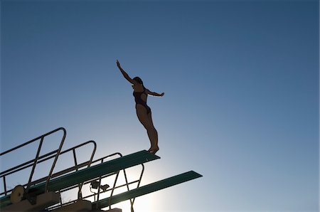 Female swimmer standing on diving board at sunset Stock Photo - Premium Royalty-Free, Code: 693-03707070