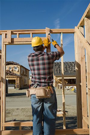 Construction worker hammering nail on construction site Foto de stock - Sin royalties Premium, Código: 693-03707187