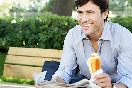 Businessman with sandwich and newspaper sitting on park bench, close-up Stock Photo - Premium Royalty-Free, Code: 693-03707584