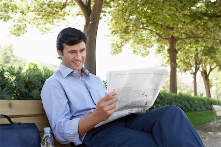 Businessman reading newspaper on park bench Stock Photo - Premium Royalty-Free, Code: 693-03707582