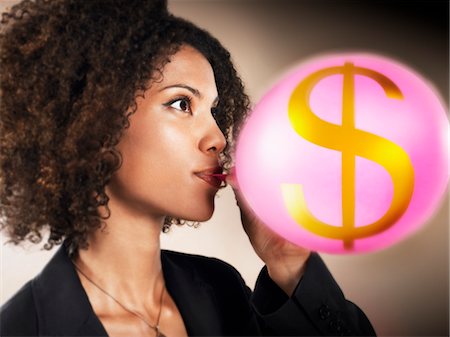 Businesswoman blowing up balloon with dollar sign on, head and shoulders Stock Photo - Premium Royalty-Free, Code: 693-03707722
