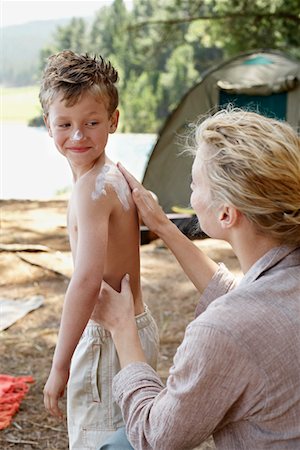 Mother Applying Suntan Lotion on Son (7-9) at campsite. Stock Photo - Premium Royalty-Free, Code: 693-03707821