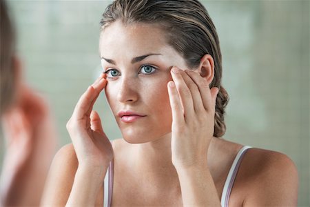 Woman rubbing temples in front of mirror Stock Photo - Premium Royalty-Free, Code: 693-03707844