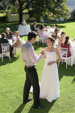 Mid adult bride and groom in garden, toasting among wedding guests Stock Photo - Premium Royalty-Free, Code: 693-03707859