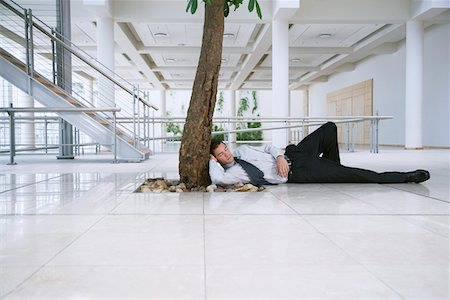 Businessman sleeping under tree outside office Stock Photo - Premium Royalty-Free, Code: 693-03707852