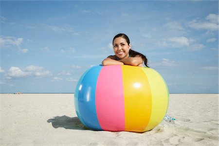 Teenage girl (16-17) sitting behind beach ball on beach, portrait Stock Photo - Premium Royalty-Free, Code: 693-03707941