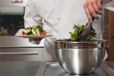 provisiones - Mid- adult chef lifts leaf vegetables onto side plate Foto de stock - Sin royalties Premium, Código: 693-03782526