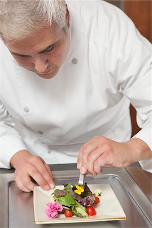 Mid- adult chef arranges edible flowers on salad Stock Photo - Premium Royalty-Free, Code: 693-03782537
