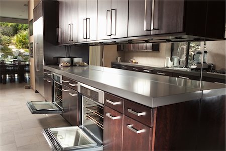 plan de travail (cuisine) - Île de cuisine en bois foncé avec des portes de four ouvertes Photographie de stock - Premium Libres de Droits, Code: 693-03782549