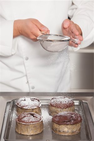 Mid- adult chef sieves icing sugar over chocolate cakes Stock Photo - Premium Royalty-Free, Code: 693-03782541