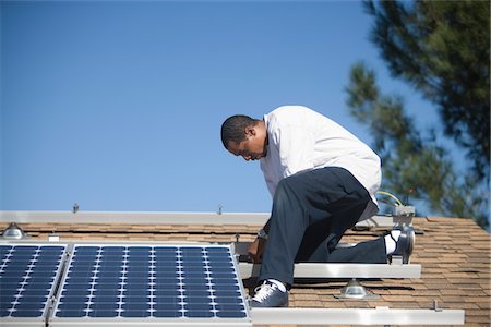 solaire - Un homme sur un toit travaillant sur des panneaux solaire Photographie de stock - Premium Libres de Droits, Code: 693-03782680