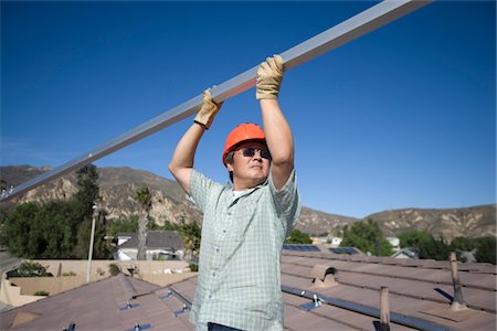 simsearch:693-03474515,k - A man lifting a large metal pole on a roof top Stock Photo - Premium Royalty-Free, Code: 693-03782692