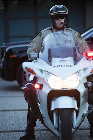 pic of policeman - Patrol officer sits on motorcycle with hazrd lights lit Stock Photo - Premium Royalty-Free, Code: 693-03782768