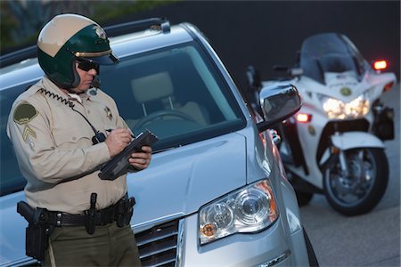 police man photos - Patrol officer stands witing ticket Stock Photo - Premium Royalty-Free, Code: 693-03782761