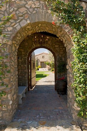 Outside archway with an open gate revealing part of a house in the distant Stock Photo - Premium Royalty-Free, Code: 693-03782974