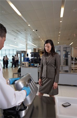 Agent de sécurité examinant la valise de la femme au contrôle des bagages à l'aéroport Photographie de stock - Rights-Managed, Code: 700-05821727