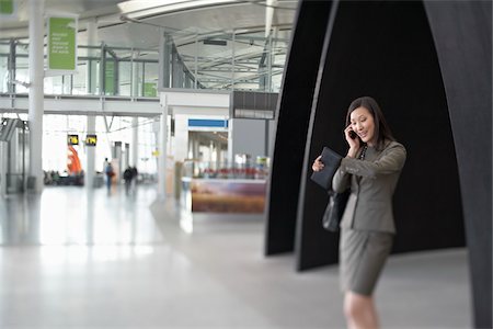 simsearch:700-05756432,k - Femme d'affaires parlait au téléphone cellulaire dans le Terminal de l'aéroport Photographie de stock - Rights-Managed, Code: 700-05821758