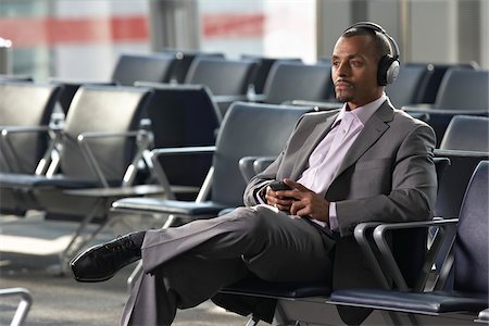 Homme d'affaires portant vos écouteurs dans l'espace d'attente de l'aéroport Photographie de stock - Rights-Managed, Code: 700-05821764