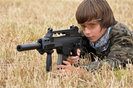 Boy Lying in Ground Aiming Gun Foto de stock - Con derechos protegidos, Código: 700-06170360