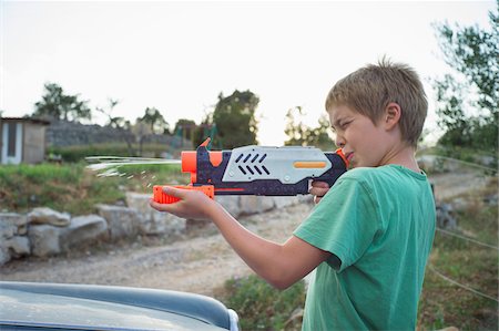 Boy Aiming and Shooting Water Gun Stockbilder - Lizenzpflichtiges, Bildnummer: 700-06452155