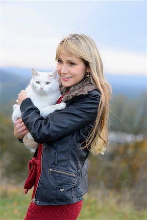 domesticate cats - Woman with Blond Hair and Wearing Leather Jacket Outdoors Holding White Cat Stock Photo - Rights-Managed, Code: 700-06531489